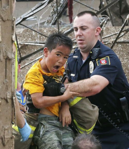 A boy is pulled from beneath a collapsed wall at the Plaza Towers Elementary School following a tornado in Moore, Okla., Monday, May 20, 2013. A tornado as much as a mile (1.6 kilometer) wide with winds up to 200 mph (320 kph) roared through the Oklahoma City suburbs Monday, flattening entire neighborhoods, setting buildings on fire and landing a direct blow on the elementary school. (AP Photo Sue Ogrocki)